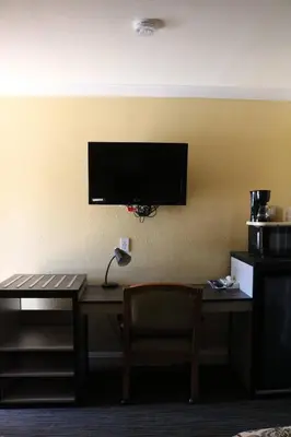 a room with a desk and a television on a wall at Timberline Motel in Lone Pine