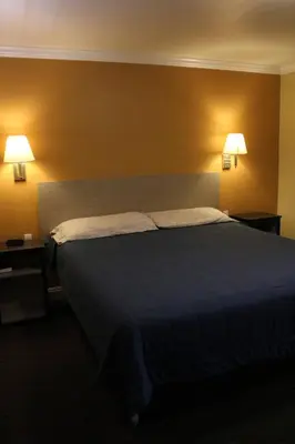 a bedroom with a large bed with two lamps on the wall at Timberline Motel in Lone Pine