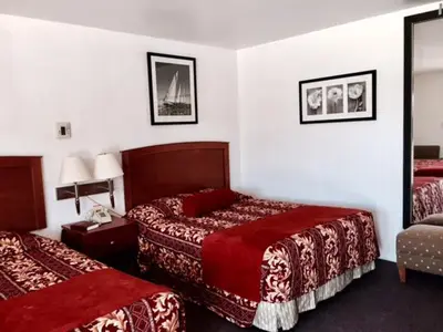 a hotel room with two beds and a mirror at Maple Inn and Suites Los Banos in Los Banos