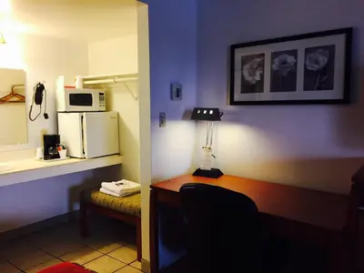 a room with a desk with a microwave and a refrigerator at Maple Inn and Suites Los Banos in Los Banos