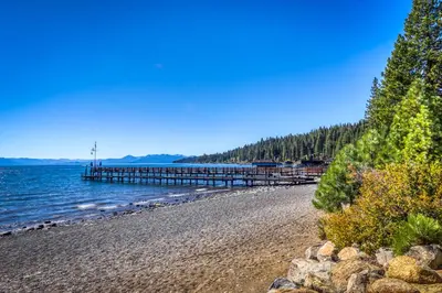 a beach with a pier and water and trees at Tahoe City Retreat in Lake Forest