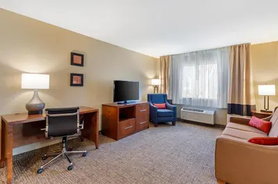 a hotel room with a desk and a couch and a tv at Comfort Inn & Suites Rocklin - Roseville in Rocklin