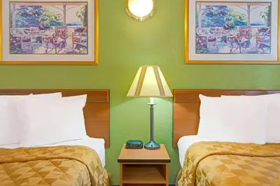 a hotel room with two beds and a table with a lamp at Travelodge by Wyndham Sacramento / Rancho Cordova in Sacramento