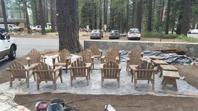 a group of wooden chairs and tables in front of a tree at Emerald Bay Lodge in South Lake Tahoe