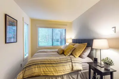 a bedroom with a bed with yellow pillows and a window at Casa del Lago in Tyrolian Village