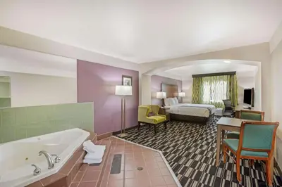 a hotel room with a tub and a bedroom at La Quinta by Wyndham Modesto Salida in Modesto