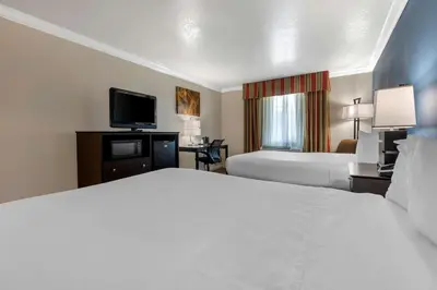 a hotel room with two beds and a flat screen tv at Best Western Colonial Inn in Selma