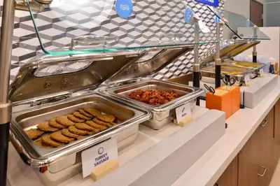 a buffet line with trays of food on a counter at Holiday Inn Express Hotel & Suites San Jose-Morgan Hill by IHG in Morgan Hill