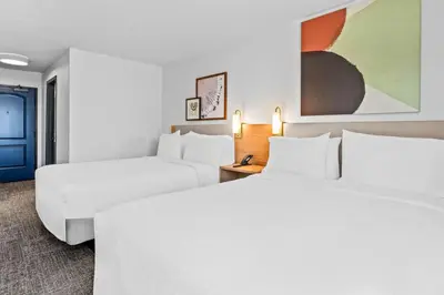 a hotel room with two beds and a blue door at Spark by Hilton Modesto in Modesto