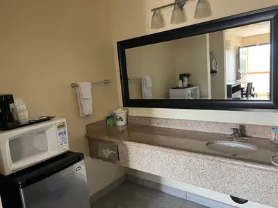 a bathroom with a sink and a mirror and a microwave at Yosemite Sierra Inn in Oakhurst