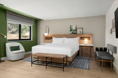a hotel room with a bed and a chair at The Inelle, Oakhurst Yosemite, a Tribute Portfolio Hotel in Oakhurst