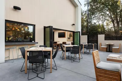a patio with tables and chairs and windows at The Inelle, Oakhurst Yosemite, a Tribute Portfolio Hotel in Oakhurst