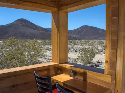 a room with a table and two chairs and mountains at Panamint Springs Motel & Tents in Panamint Springs