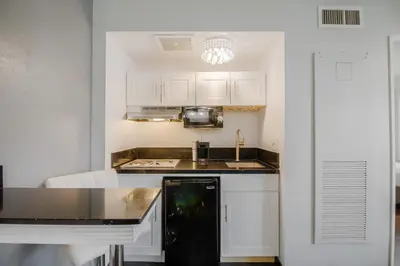 a kitchen with white cabinets and a black counter top at Lions Gate Hotel in Sacramento