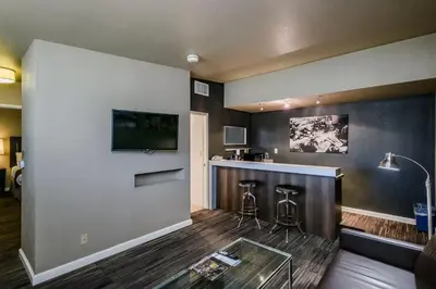 a lobby with a bar with stools and a tv at Lions Gate Hotel in Sacramento