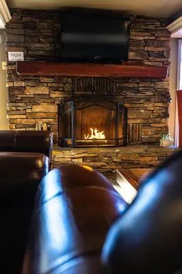 a living room with a fireplace and a leather couch at The Mammoth Creek Inn in Mammoth Lakes
