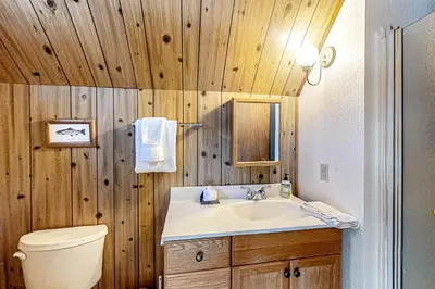 a bathroom with a sink and a toilet and wooden walls at Picture Perfect Chalet in Prosser Lakeview Estates
