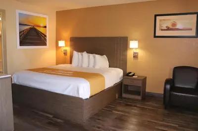a hotel room with a bed and a chair at Days Inn by Wyndham Fresno South in Fresno