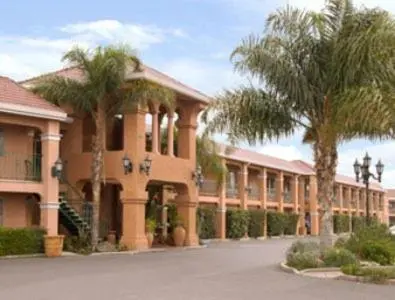 a large building with palm trees in front of it at Merced Inn & Suites in Merced