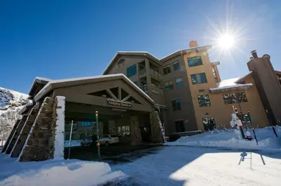 a building in the snow with the sun behind it at Kirkwood Mountain Resort by Vail Resorts in Kirkwood