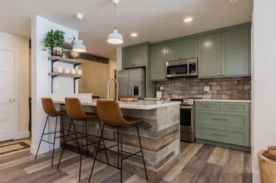 a kitchen with green cabinets and a counter with bar stools at Crestview 35 in Mammoth Lakes
