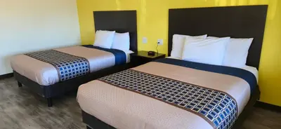 two beds in a hotel room with yellow walls at Grapevine Inn in Lodi