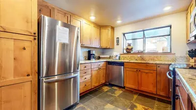 a kitchen with wooden cabinets and a stainless steel refrigerator at Snowflower #26 Condo in Mammoth Lakes