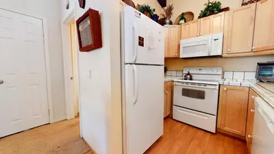 a kitchen with white appliances and wooden cabinets at Chateau De Montagne #23 Condo in Mammoth Lakes