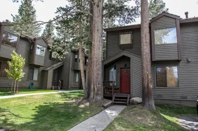 a house with a red door and trees at Forest Creek #28 Condo in Mammoth Lakes