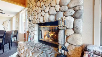 a fireplace in a living room with a stone wall at Bridges Townhome #13 Condo in Mammoth Lakes