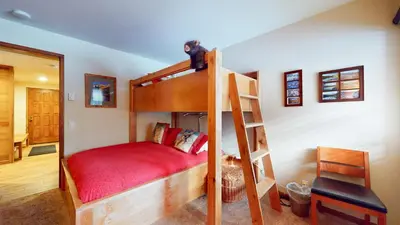a bedroom with a bunk bed with a red bedspread at Sierra Megeve #7 Condo in Mammoth Lakes