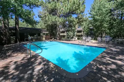 a large blue swimming pool with tables and chairs at Chateau De Montagne #17 Condo in Mammoth Lakes