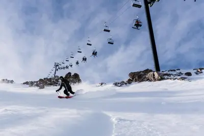 a person riding a snowboard down a snow covered slope with a ski lift at Snowcreek V #933 Townhouse in Mammoth Lakes