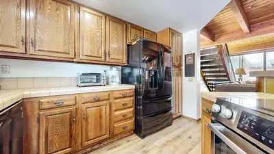 a kitchen with wooden cabinets and a black refrigerator at Snowflower #49 Condo in Mammoth Lakes