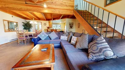 a living room with a blue couch and a staircase at Snowflower #74 Condo in Mammoth Lakes