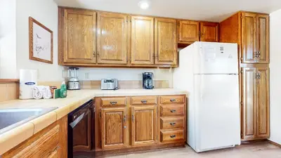 a kitchen with wooden cabinets and a white refrigerator at Snowflower #68 Condo in Mammoth Lakes