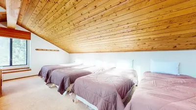 a row of beds in a room with a wooden ceiling at Snowflower #68 Condo in Mammoth Lakes