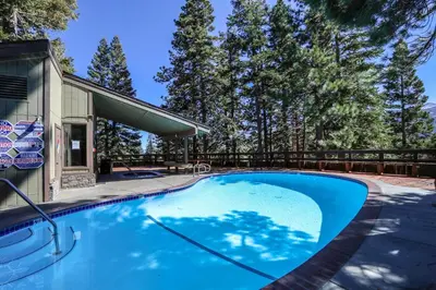 a swimming pool in front of a house with trees at Hidden Valley #15 Condo in Mammoth Lakes
