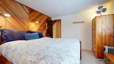 a bedroom with a bed and a wooden wall at Sierra Manors #75 Condo in Mammoth Lakes