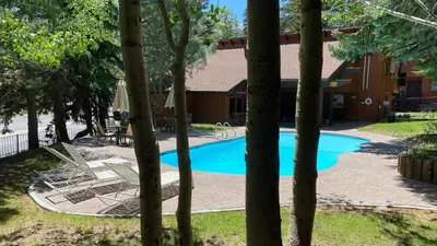 a swimming pool with lounge chairs in a yard at Mammoth West #106 Condo in Mammoth Lakes