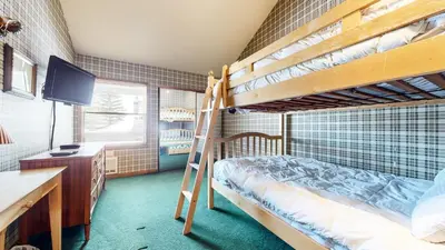 a bedroom with two bunk beds and a desk and a television at Sierra Megeve #8 Condo in Mammoth Lakes