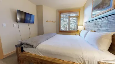 a bedroom with a bed and a flat screen tv at Sunstone #127 Condo in Mammoth Lakes