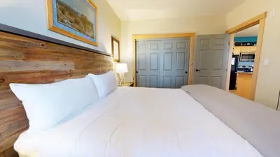 a bedroom with a large white bed with a wooden headboard at Sunstone #127 Condo in Mammoth Lakes