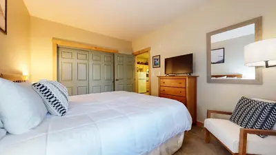 a bedroom with a white bed and a chair at Sunstone #114 Condo in Mammoth Lakes