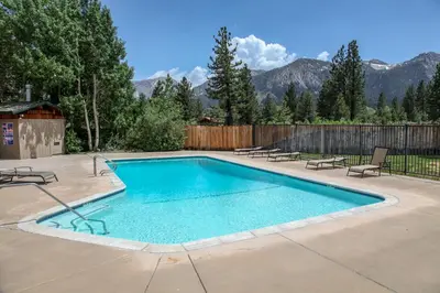 a swimming pool in a backyard with mountains in the background at Chateau Blanc #25 Condo in Mammoth Lakes