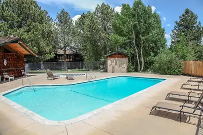 a swimming pool with chairs and a house at Chateau Blanc #25 Condo in Mammoth Lakes