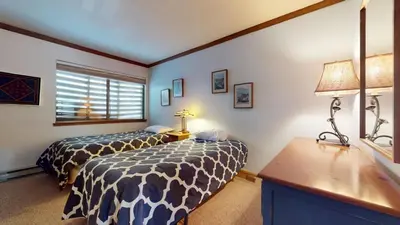 a bedroom with two beds and a desk and a window at Mammoth West #101 Condo in Mammoth Lakes