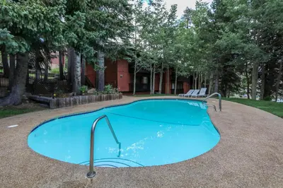 a swimming pool with a bench in front of a building at Mammoth West #124 Condo in Mammoth Lakes