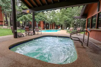 a swimming pool with chairs and a table next to a building at Mammoth West #124 Condo in Mammoth Lakes