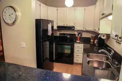 a kitchen with black appliances and a clock on the wall at Chateau De Montagne #3 Condo in Mammoth Lakes